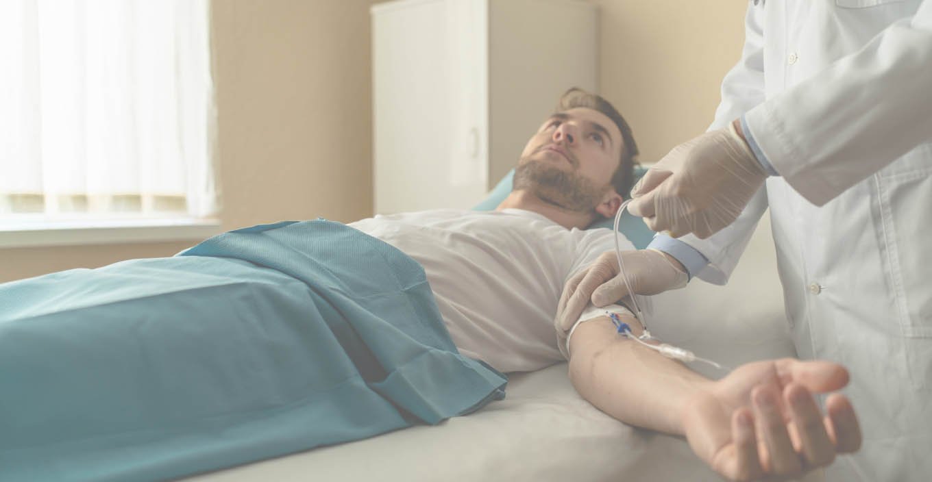 Мужчина лежит на процедуре под капельницей